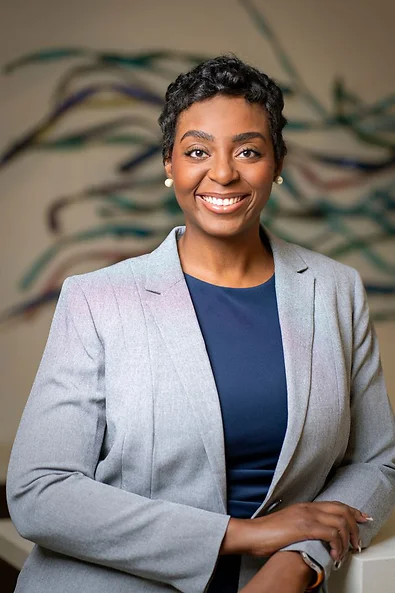 Attorney Janel Okafor smiling wearing grey jacket and blue shirt